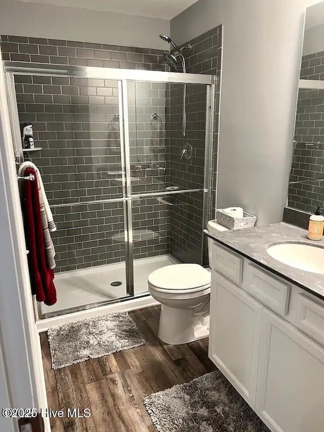 full bath with vanity, toilet, wood finished floors, and a shower stall