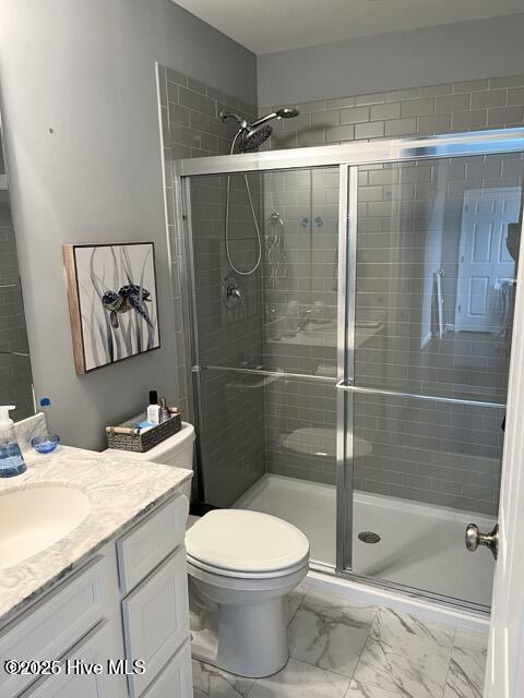 bathroom featuring toilet, marble finish floor, a stall shower, and vanity