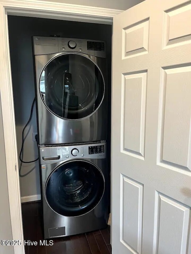 laundry room featuring laundry area, stacked washer and clothes dryer, and dark wood-type flooring