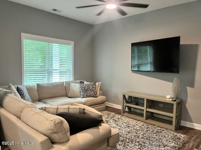 living area with visible vents, baseboards, wood finished floors, and a ceiling fan