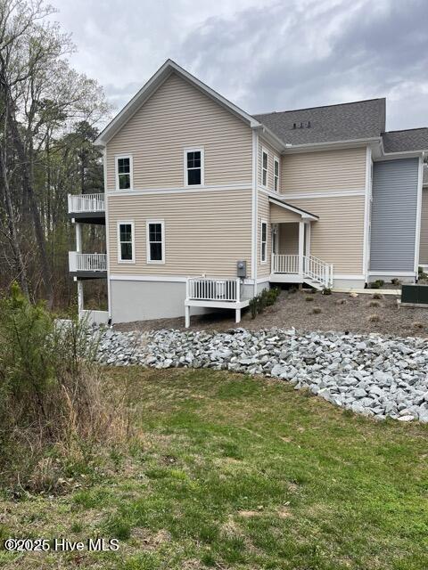 rear view of property with a balcony and a lawn