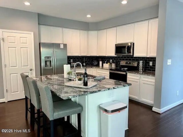 kitchen with dark stone counters, tasteful backsplash, appliances with stainless steel finishes, and white cabinets