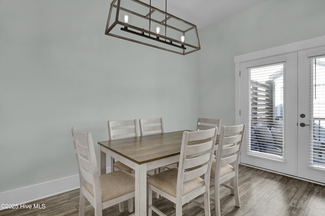 dining space featuring french doors, baseboards, an inviting chandelier, and wood finished floors