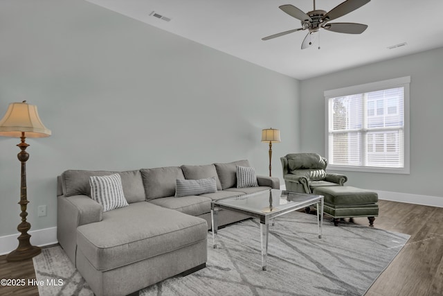 living room featuring baseboards, wood finished floors, visible vents, and ceiling fan