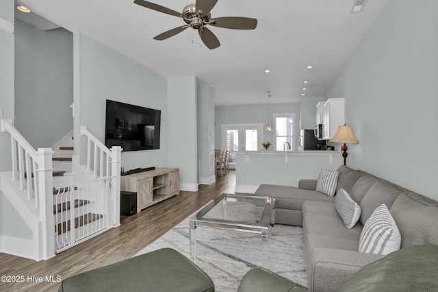 living area featuring wood finished floors, baseboards, recessed lighting, ceiling fan, and stairs