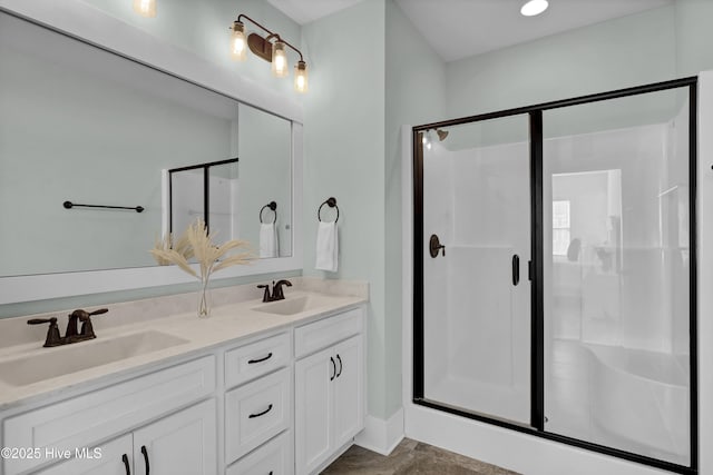 full bathroom with double vanity, a shower stall, and a sink