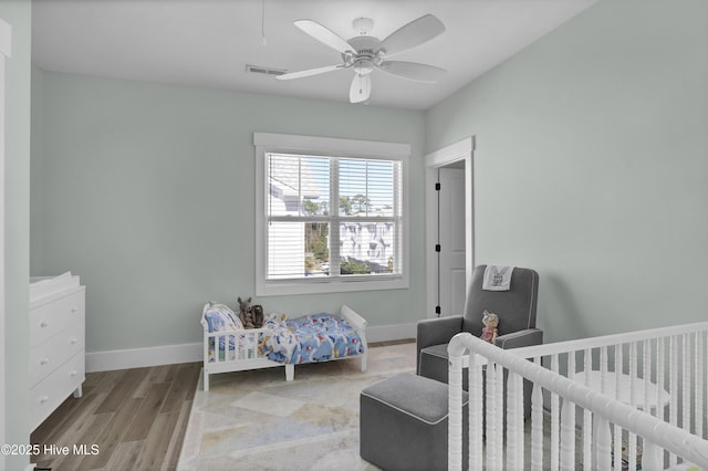 bedroom featuring ceiling fan, visible vents, baseboards, and wood finished floors