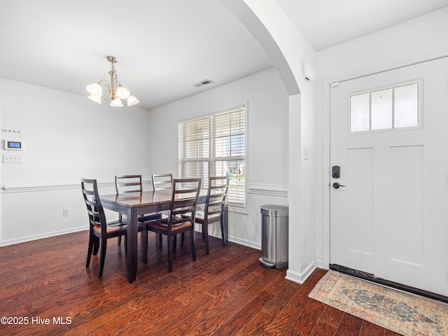 dining room featuring visible vents, a notable chandelier, dark wood-style floors, arched walkways, and baseboards