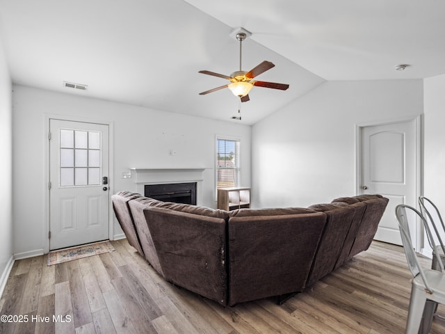 living room with visible vents, vaulted ceiling, a fireplace, wood finished floors, and a ceiling fan