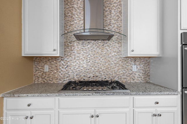 kitchen featuring stainless steel gas cooktop, white cabinetry, wall chimney range hood, and tasteful backsplash