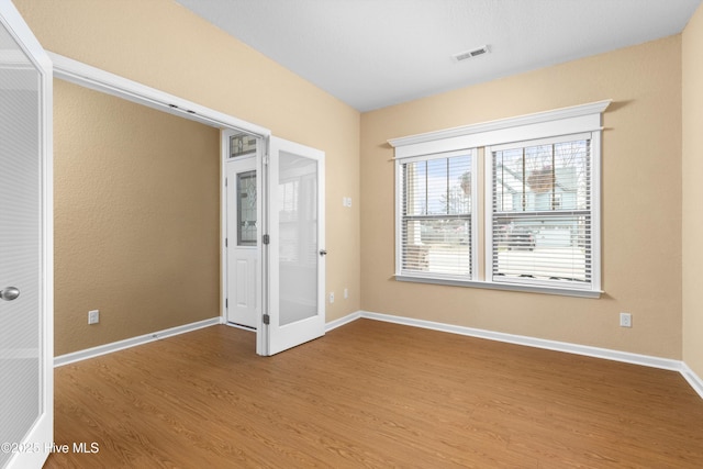 unfurnished bedroom with visible vents, baseboards, and wood finished floors