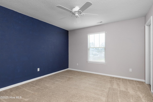 empty room featuring carpet, baseboards, visible vents, ceiling fan, and a textured ceiling