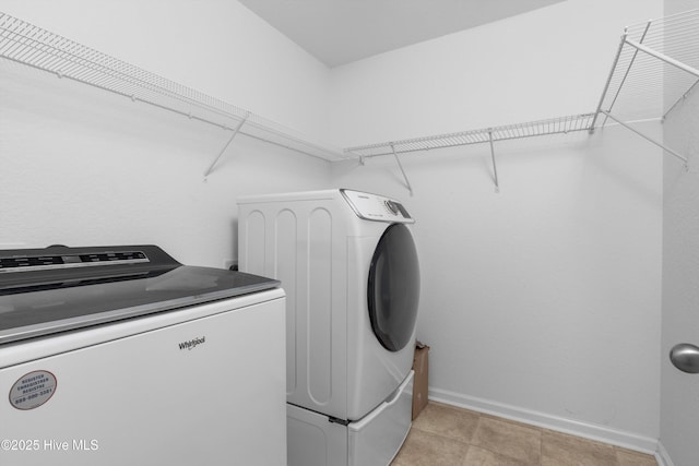 clothes washing area with laundry area, baseboards, and independent washer and dryer