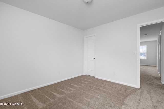 carpeted spare room featuring baseboards