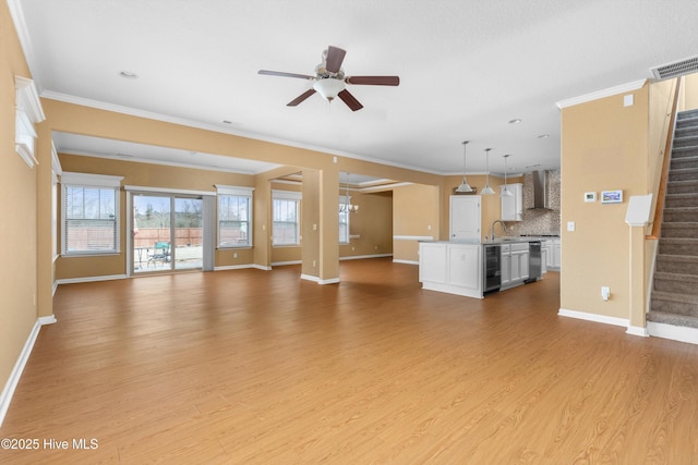 unfurnished living room featuring wood finished floors, visible vents, a sink, stairs, and ceiling fan