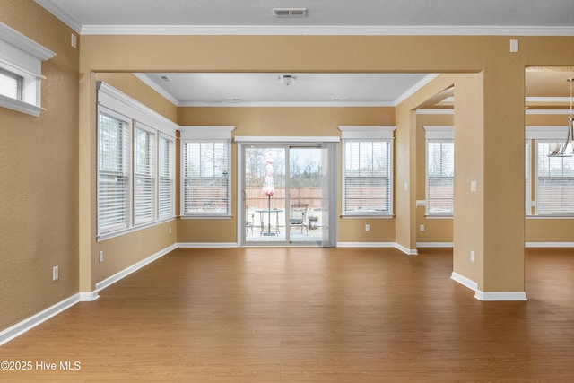 unfurnished living room featuring visible vents, crown molding, and wood finished floors