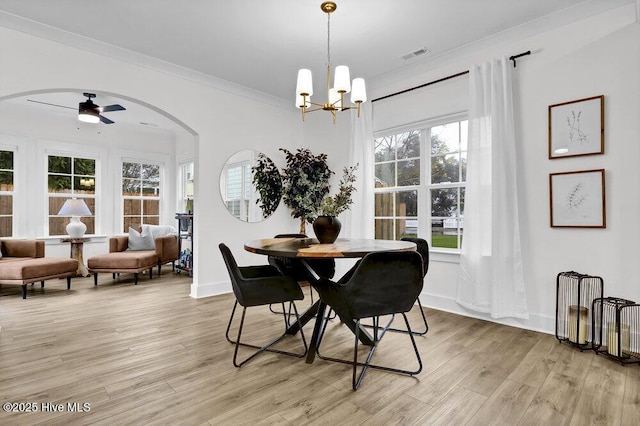 dining area featuring visible vents, ornamental molding, ceiling fan with notable chandelier, light wood-style floors, and baseboards