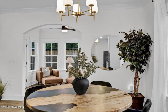 dining space with baseboards, wood finished floors, arched walkways, and ornamental molding