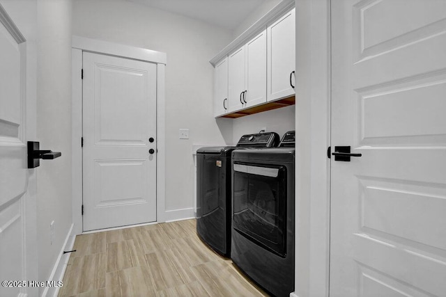 washroom featuring washing machine and clothes dryer, cabinet space, light wood-style floors, and baseboards