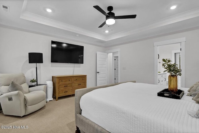 bedroom with a tray ceiling, light colored carpet, visible vents, and ornamental molding