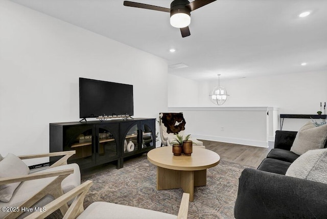 living room with recessed lighting, wood finished floors, and ceiling fan with notable chandelier