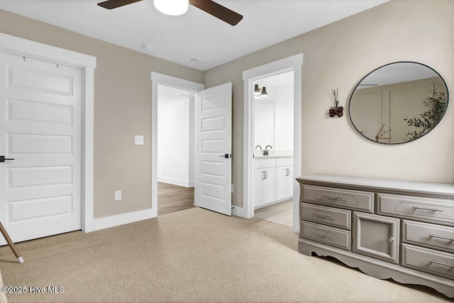 unfurnished bedroom with connected bathroom, baseboards, light colored carpet, a ceiling fan, and a sink