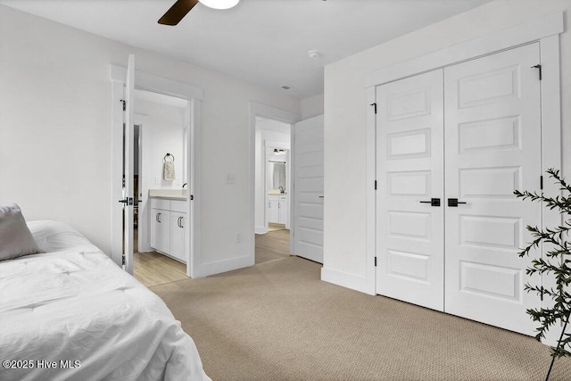 bedroom with baseboards, ceiling fan, a closet, ensuite bathroom, and light colored carpet