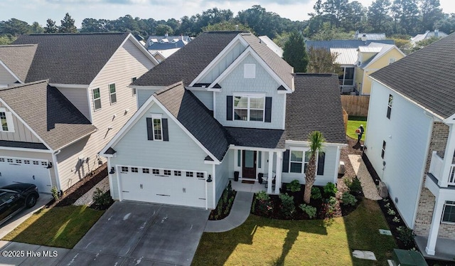 traditional-style home featuring driveway, a shingled roof, a front yard, and fence