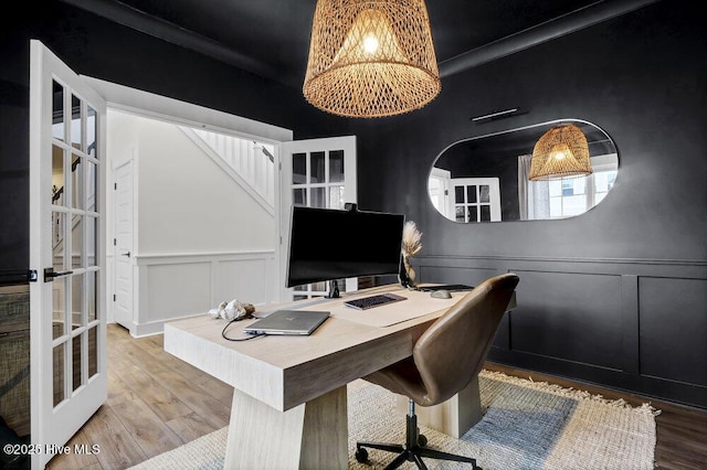 office featuring a decorative wall, wood finished floors, a chandelier, and wainscoting