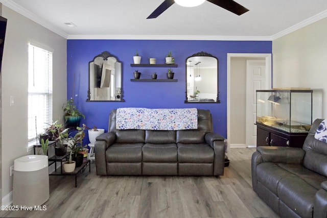 living room featuring a ceiling fan, wood finished floors, baseboards, visible vents, and crown molding