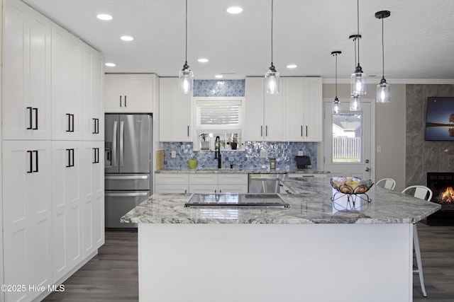 kitchen featuring dark wood finished floors, appliances with stainless steel finishes, a breakfast bar, and a sink