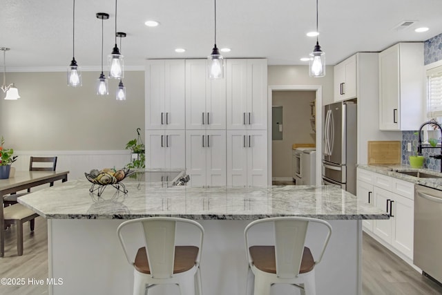 kitchen with a sink, a breakfast bar, visible vents, and stainless steel appliances