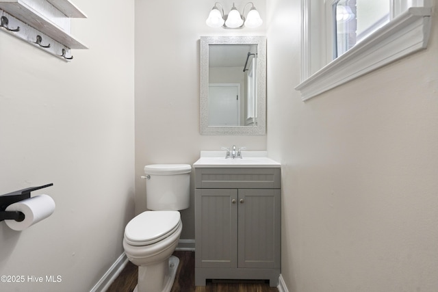 bathroom with toilet, vanity, baseboards, and wood finished floors