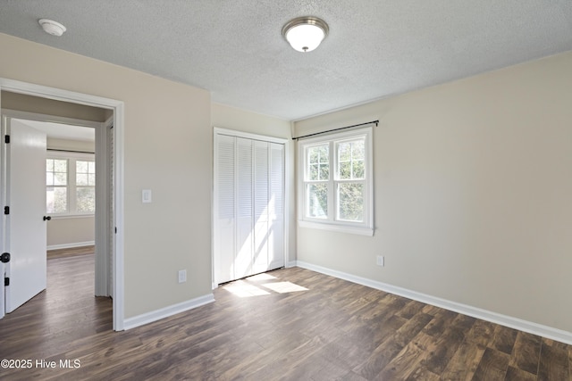 unfurnished bedroom with a closet, baseboards, dark wood-type flooring, and a textured ceiling