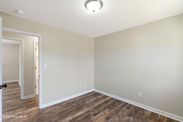 spare room with baseboards, a textured ceiling, and dark wood finished floors