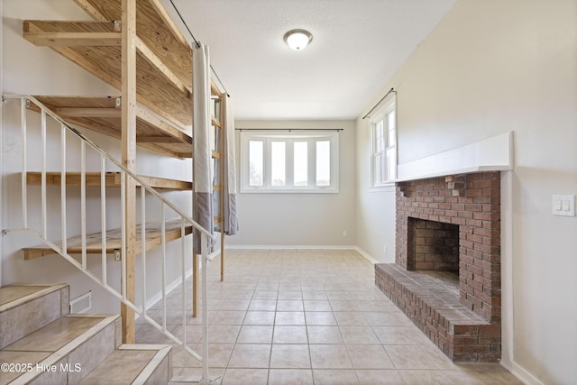 interior space featuring tile patterned flooring, a brick fireplace, and baseboards