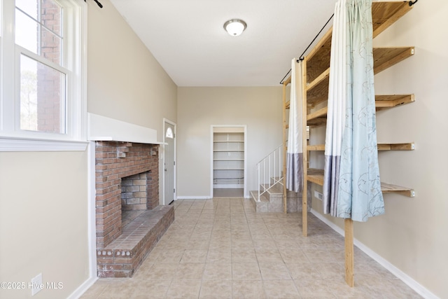 unfurnished living room with stairs, tile patterned floors, a fireplace, and baseboards