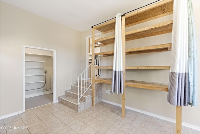 interior space with stairway, light tile patterned floors, and baseboards