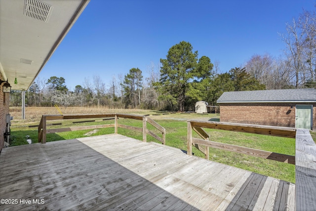 deck featuring an outbuilding, visible vents, a storage unit, a rural view, and a lawn