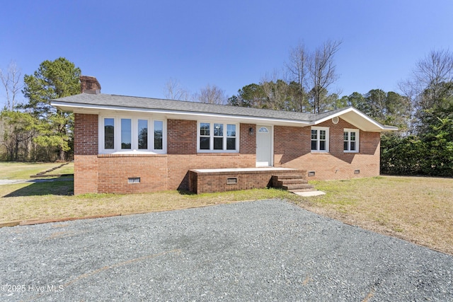 view of front of property featuring crawl space, a chimney, a front yard, and brick siding