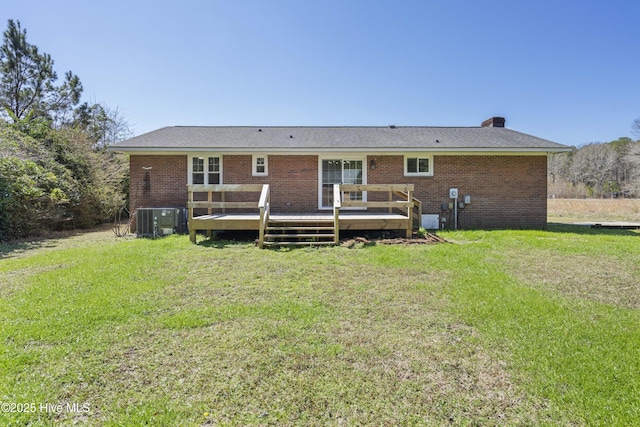 rear view of house with a deck, a yard, brick siding, and central AC