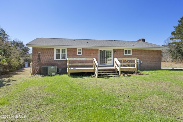 rear view of property featuring brick siding, central air condition unit, a lawn, and a wooden deck