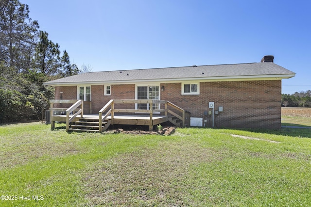 back of house with a yard, brick siding, a wooden deck, and a chimney