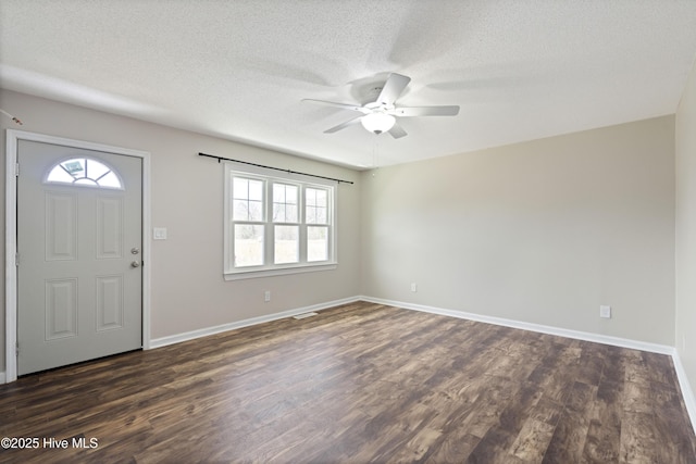 entryway with a textured ceiling, dark wood-style floors, a wealth of natural light, and ceiling fan