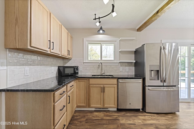 kitchen with dark wood-style flooring, a sink, decorative backsplash, appliances with stainless steel finishes, and dark countertops