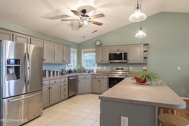 kitchen with gray cabinetry, a breakfast bar area, appliances with stainless steel finishes, a peninsula, and hanging light fixtures