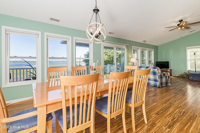 dining room with visible vents, ceiling fan with notable chandelier, wood finished floors, baseboards, and vaulted ceiling