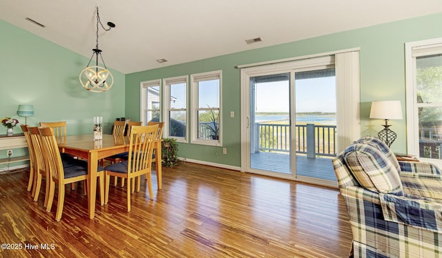 dining space featuring visible vents, a healthy amount of sunlight, wood finished floors, and an inviting chandelier