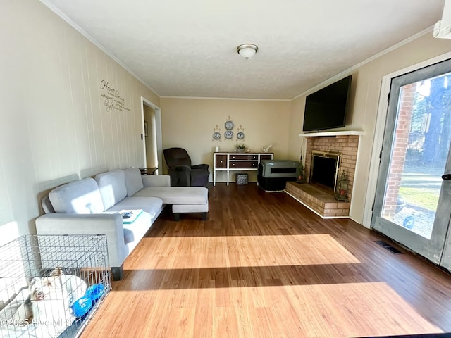 living room with visible vents, crown molding, and wood finished floors