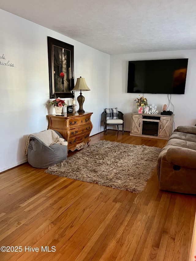 living room featuring a textured ceiling, baseboards, and wood finished floors